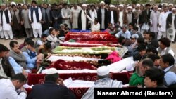 People gather to attend a funeral for the victims of the market blast at a graveyard in Quetta on April 12.