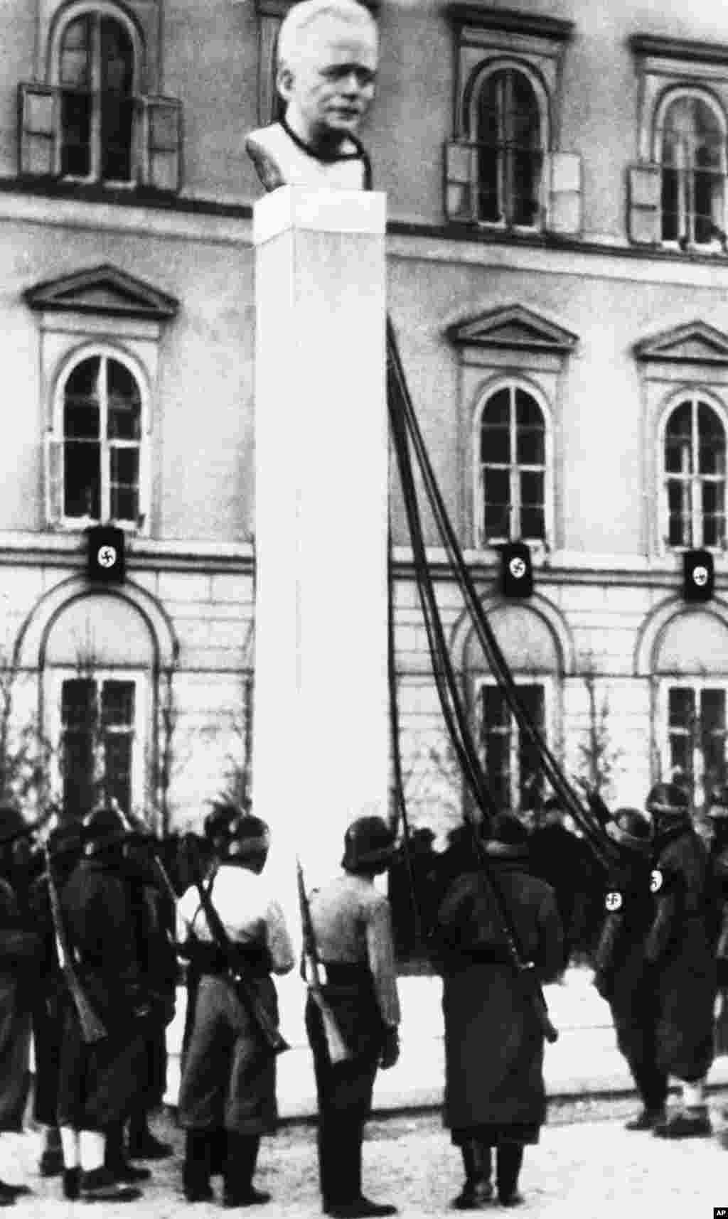 Нацистички трупи ја чекаат наредбата да ја срушат бистата на австрискиот канцелар Енгелберт Долфус по анексијата на Австрија од страна на нацистичка Германија во 1938 година.