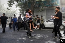 Një burrë e bart me nxitim një vajzë nga një vend ku kishte ndodhur një shpërthim në Teheran, gjatë sulmeve izraelite në kryeqytetin iranian, 15 qershor.
