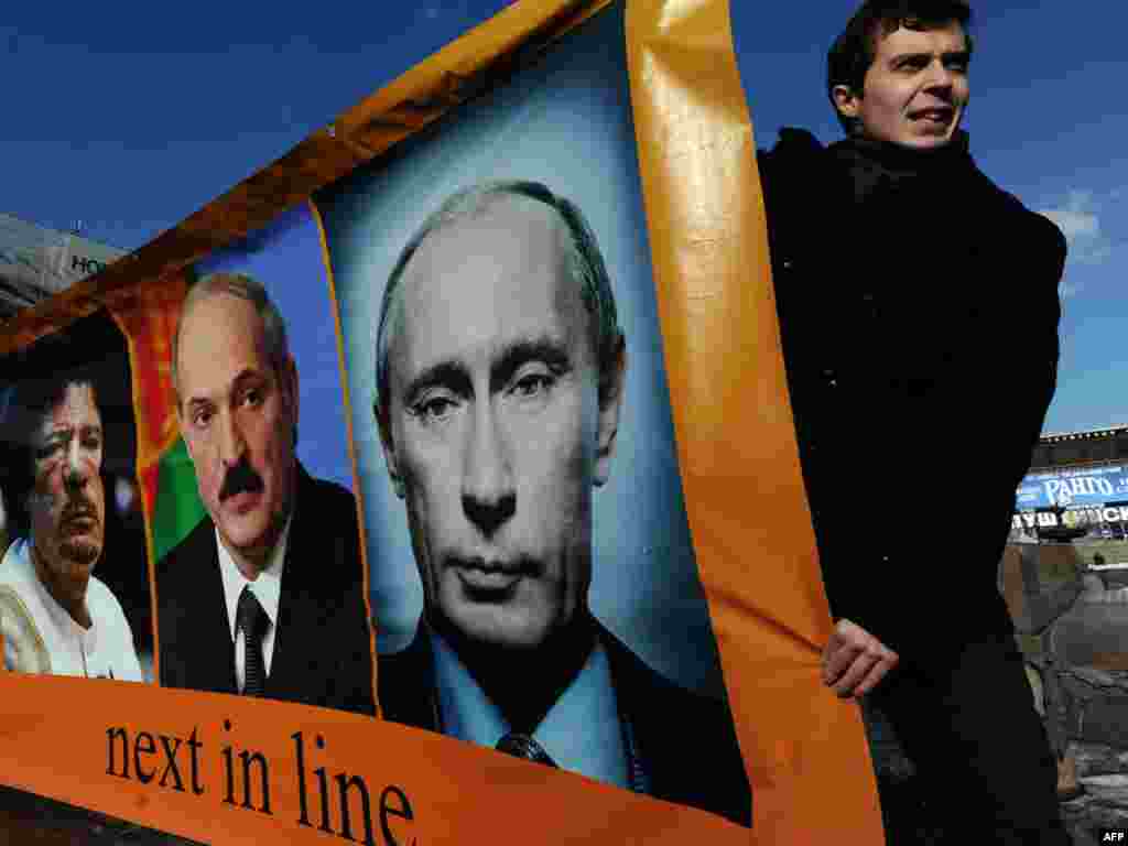 Активисти на опозицијата во Москва носат фотографии на премиерот Владимир Путин, либискиот лидер, Моамер Гадафи и белорускиот претседател, Александар Лукашенко со текст &bdquo;Следниот во низата&ldquo;, на 13 март. 
