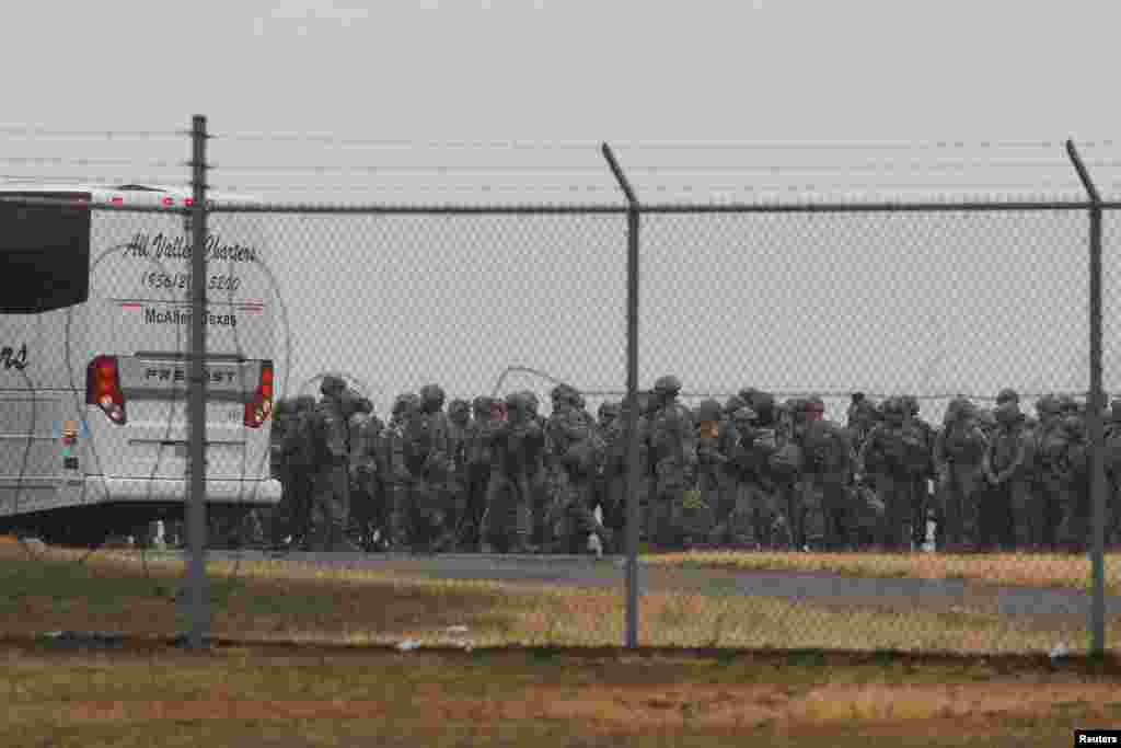 Anëtarët e Gardës Kombëtare të Teksasit ecin në radhë për të hipur në një autobus pasi mbërritën në Aeroportin Ndërkombëtar të MekAllenit, për të ndihmuar në sigurinë përgjatë kufirit me Meksikën, në Teksas, 27 janar. 