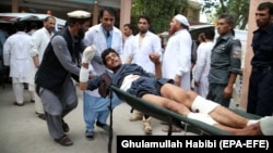 People carry a man who was injured in a suicide bomb attack at an election-campaign rally in eastern Afghanistan's Kama district on October 2. 