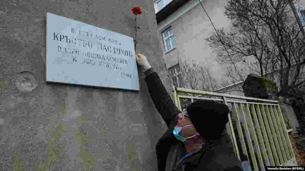 Мъж с предпазна маска закрепва цвете на паметната плоча на Кръстьо Пастухов, поставена тук през 1998 година. Адресът е ул. "Бенковски" 36. Пастухов (1874-1949) е един от лидерите на българските социалдемократи и министър на вътрешните работи и народното здраве през 1919 г. Той е противник на управлението на Борис Трети през 30-те и началото на 40-те години. След преврата на 9 септември 1944 г. той е осъден на 5 години затвор и умира като затворник на 25 август 1949 г.