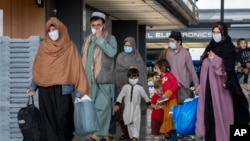 Families evacuated from Kabul, Afghanistan, walk through the terminal to board a bus after they arrived at Washington Dulles International Airport, in Chantilly, Va., Sept. 1, 2021