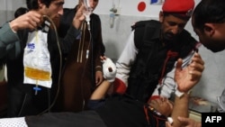 Pakistani paramilitary soldiers assist an injured colleague as he is being treated at a hospital in Peshawar.
