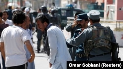 Afghan policemen try to comfort a man whose relatives were stuck at the site of a suicide attack followed by a clash between Afghan forces and insurgents after an attack on a Shi'ite Muslim mosque in Kabul on August 25.