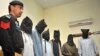FILE: A Pakistani policeman stands guard alongside suspects who allegedly killed Sikh politician Sardar Soran Singh during a press conference after their arrest in Peshawar, on April 25.