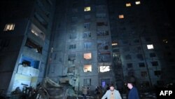Локални жители стојат во двор на оштетената станбена зграда по ракетниот напад во Харкив доцна на 21 септември 2024 година, среде руската инвазија врз Украина.