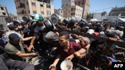 Palestinezët duke marrë ushqime në një qendrë të shpërndarjes në kampin e refugjatëve Nuseirat në pjesën qendrore të Rripit të Gazës. 19 korrik 2025. 