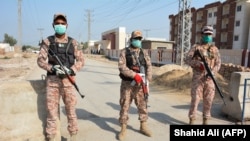 Soldiers wearing facemasks stand guard on road leading to a quarantine faciltity (R) for people returning from Iran via the Pakistan-Iran border town of Taftan to prevent the spread the coronavirus in Sukkur, a city in southern province of Sindh.