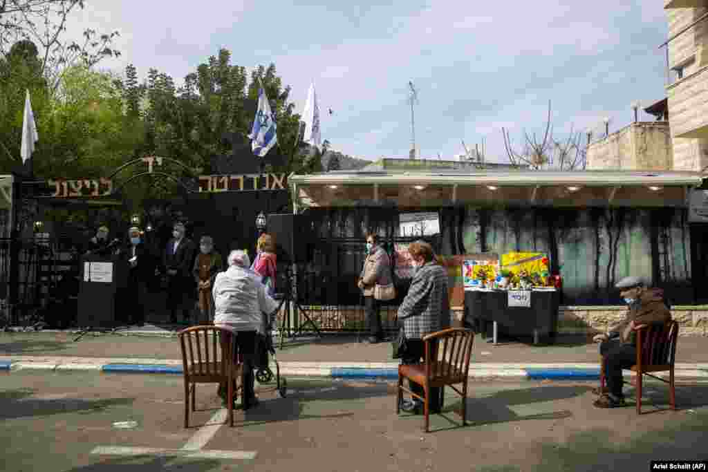 Supraviețuitori ai Holocaustului poartă mască și păstrează distanța fizică în timpul participării la ceremonia dedicată Zilei internaționale a comemorării Holocaustului din orașul Haifa, din nordul Israelului. Evenimentul a avut loc în aer liber din cauza pandemiei de COVID-19 și a faptului că țara se află în carantină. 27 ianuarie, 2021.&nbsp;
